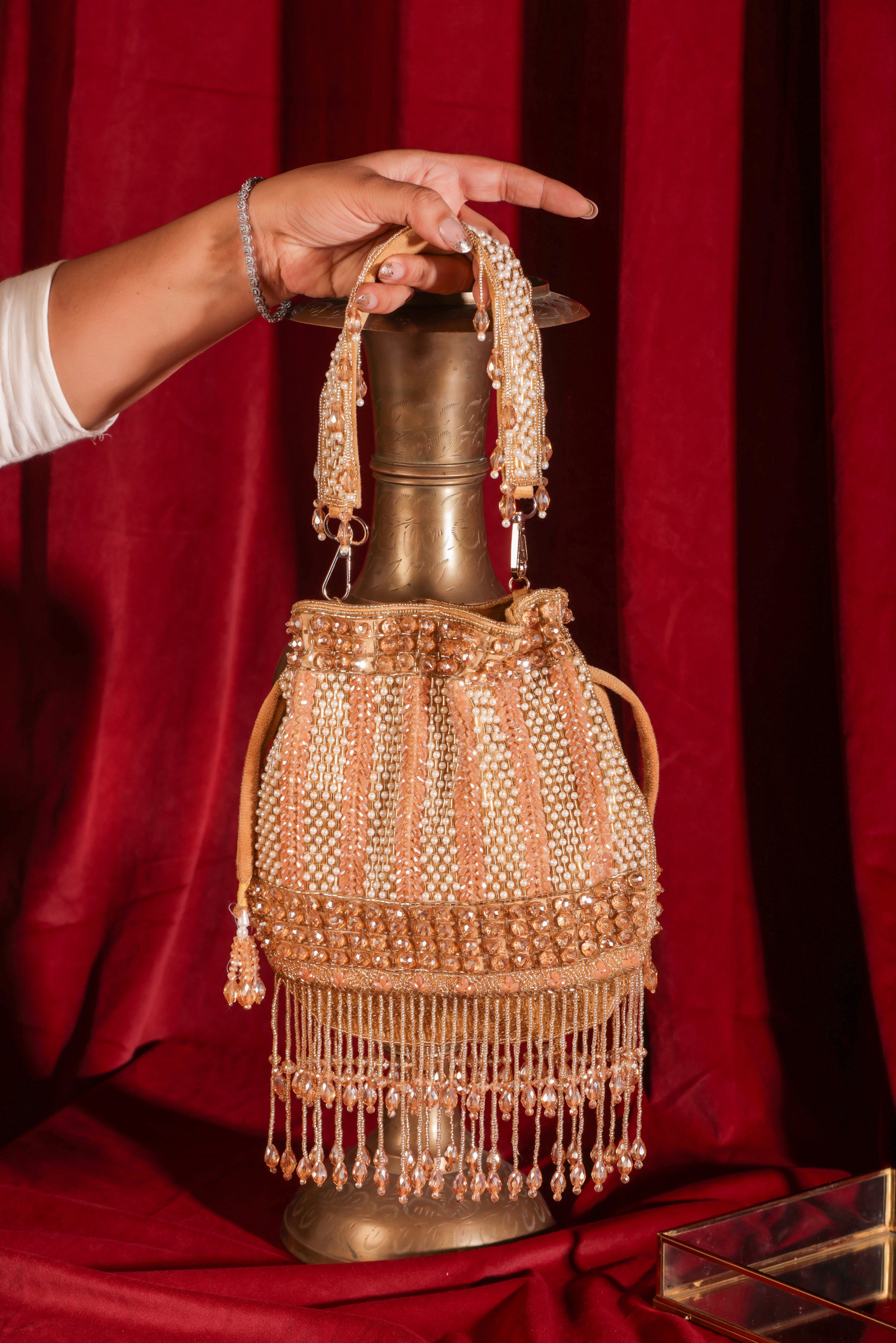 Gold potli bag with sparkling crystals and dangling crystal fringe, Noor-E-Anmol front view.