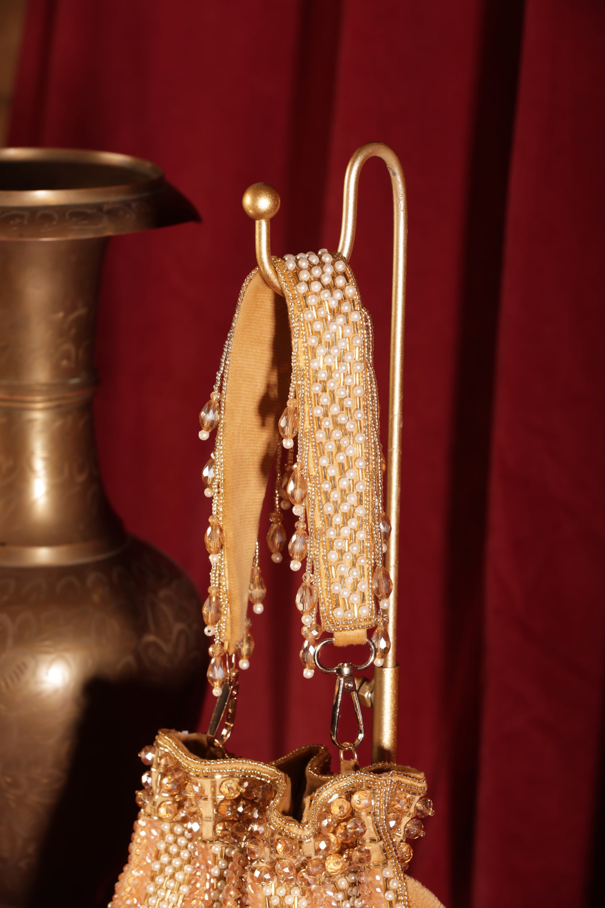 Elegant gold potli with crystals and long dangling crystal strands.