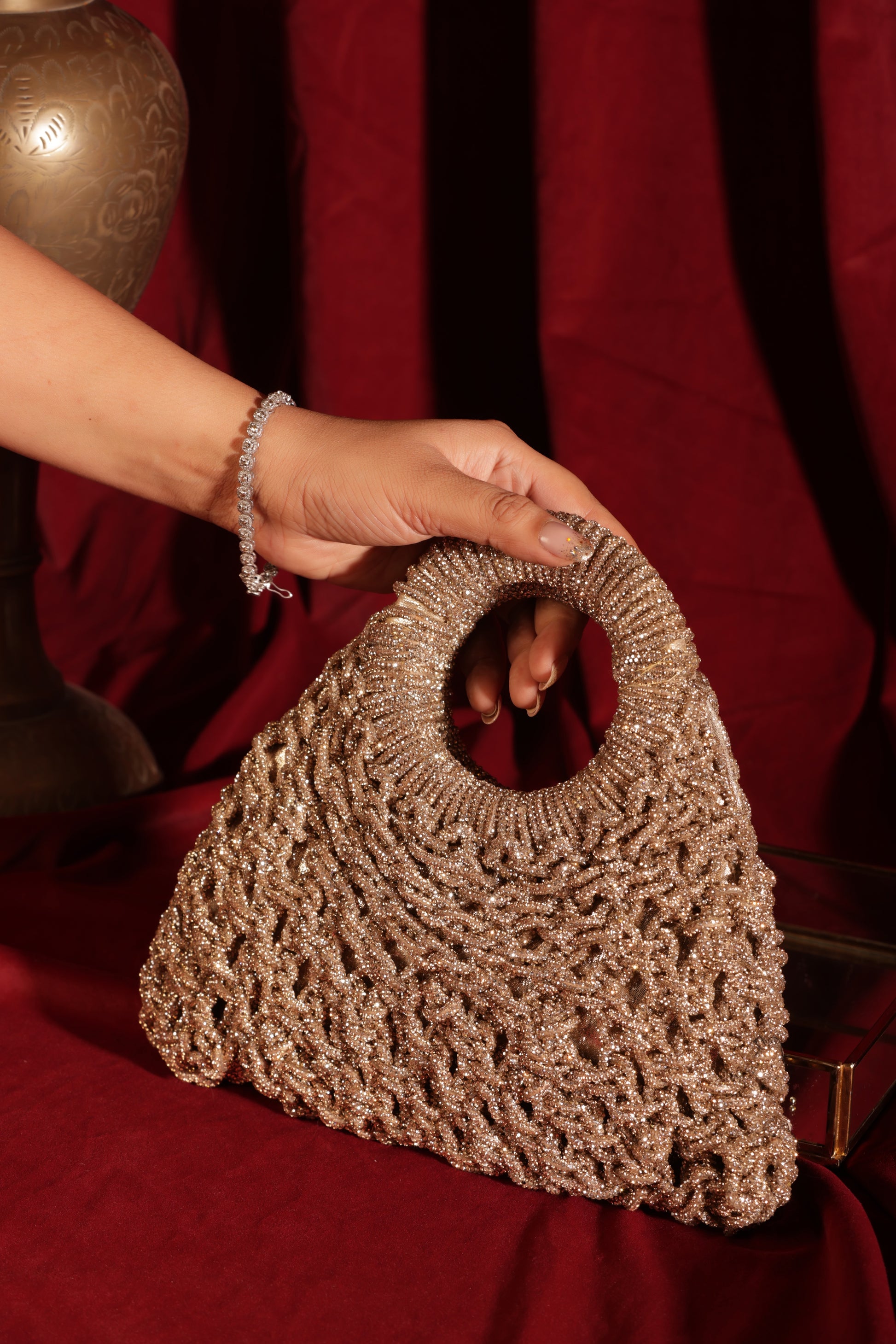 Handcrafted mesh-texture festive bags—emerald, ruby, champagne, and gold—designed with signature round handles.