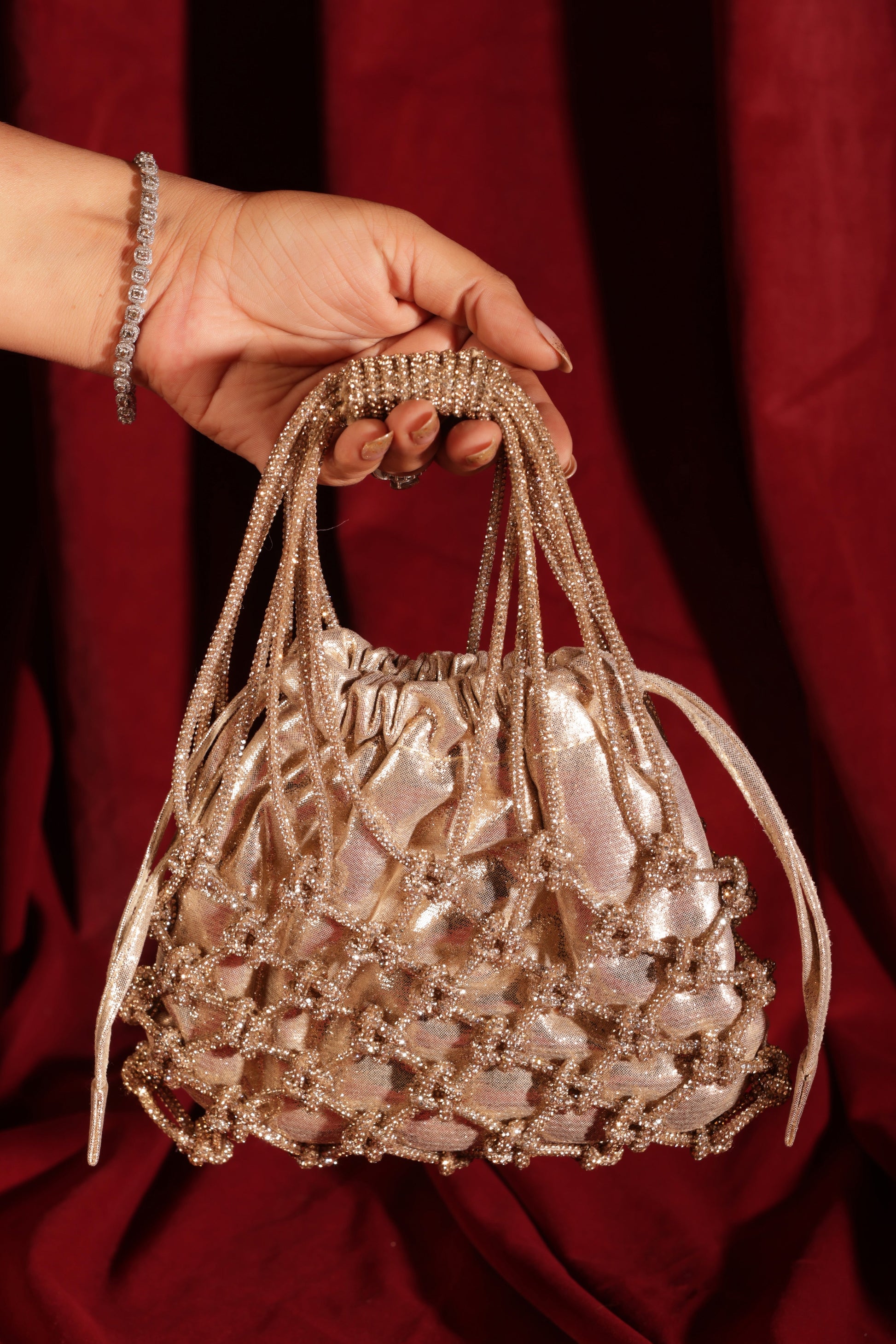 Golden potli bag with beaded net overlay and metallic shimmer finish, front view.