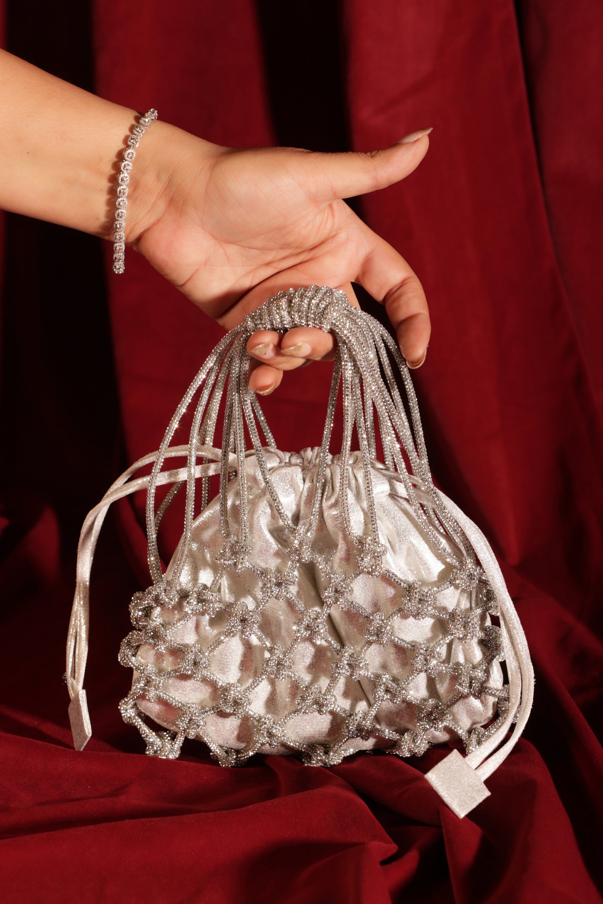Silver potli bag with beaded net overlay and metallic shimmer finish, front view.