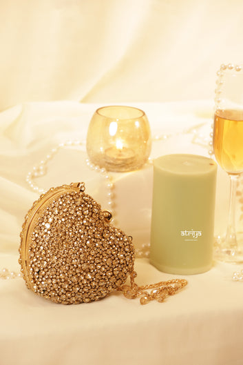 Gold heart-shaped box clutch from Atriya Jaipur, luxury handcrafted wedding handbag fully embellished with glittering gold stones. Elegant designer evening bag for brides and bridesmaids, perfect for festive wear and modern Indian wedding outfits.
