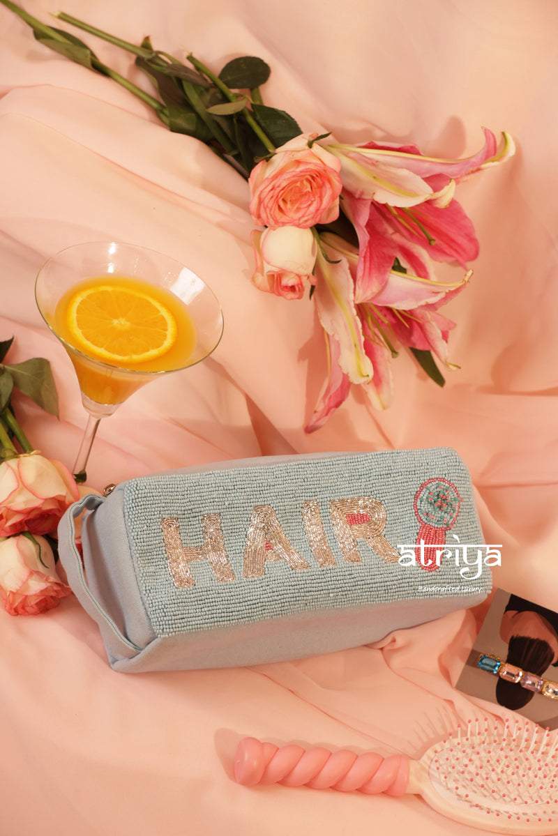 Powder blue handcrafted hair kit with full bead embroidery, rose gold HAIR lettering and beaded hair dryer charm, styled with pink florals for Atriya Jaipur.
