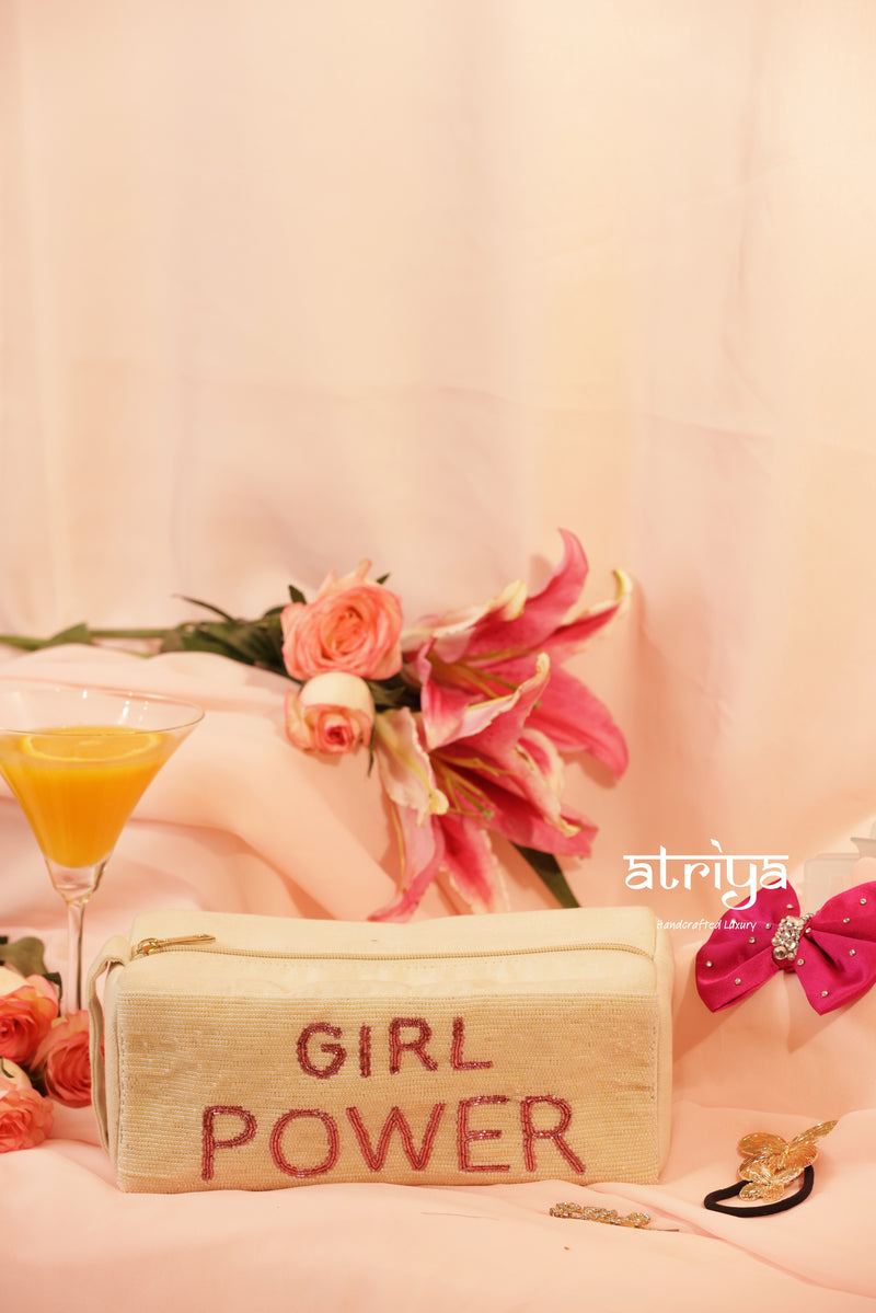 Cream ivory handcrafted pouch with bold pink beaded GIRL POWER lettering, styled with hot pink bow and gold hair accessories for Atriya Jaipur luxury collection.