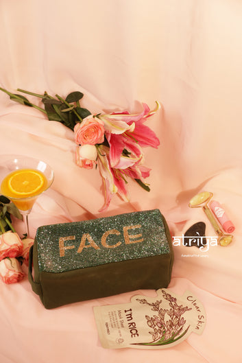 Luxury structured makeup pouch in deep olive shade with glitter detailing, styled with skincare tools and roses in soft pink editorial setup.
