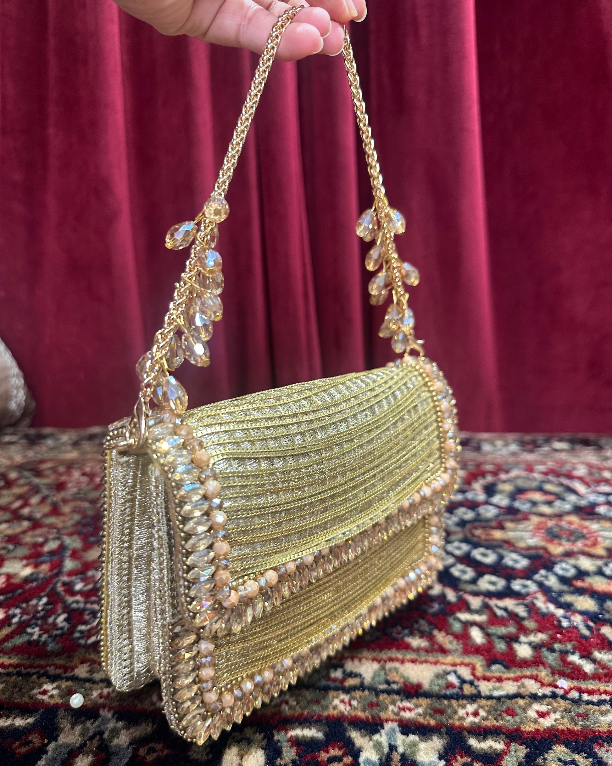 Artisanal metallic gold zari flap clutch bag with pearl accents and crystal tassel chain strap for bridal and cocktail attire